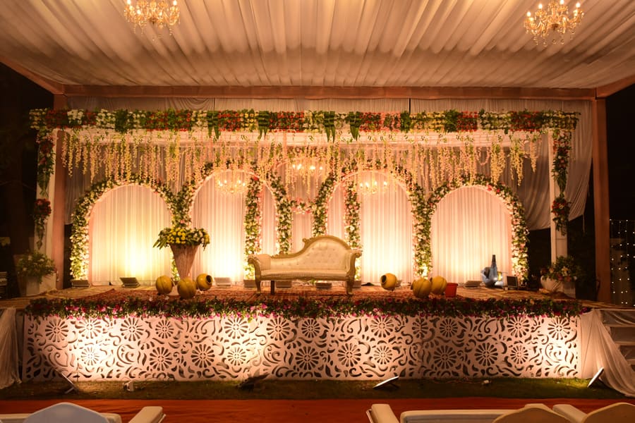 Ivory stage with floral arch backdrop inside Sanskar Banquet Hall's indoor hall