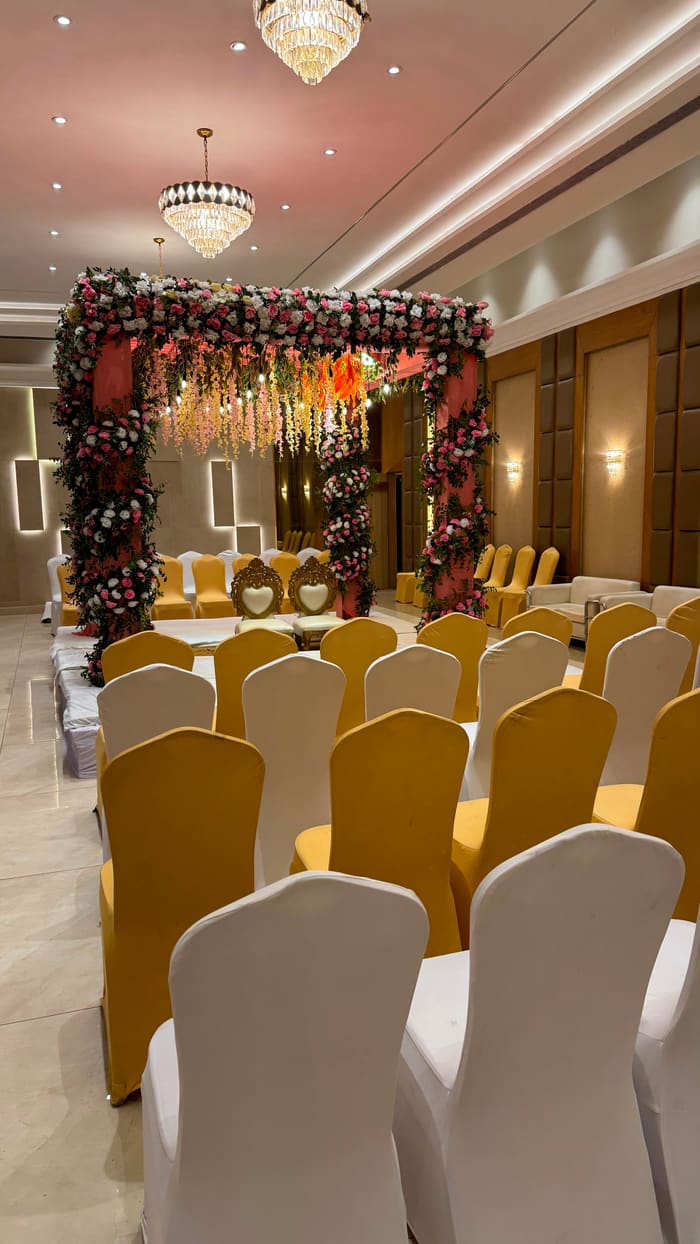 Indoor hall set up with a floral mandap and chairs